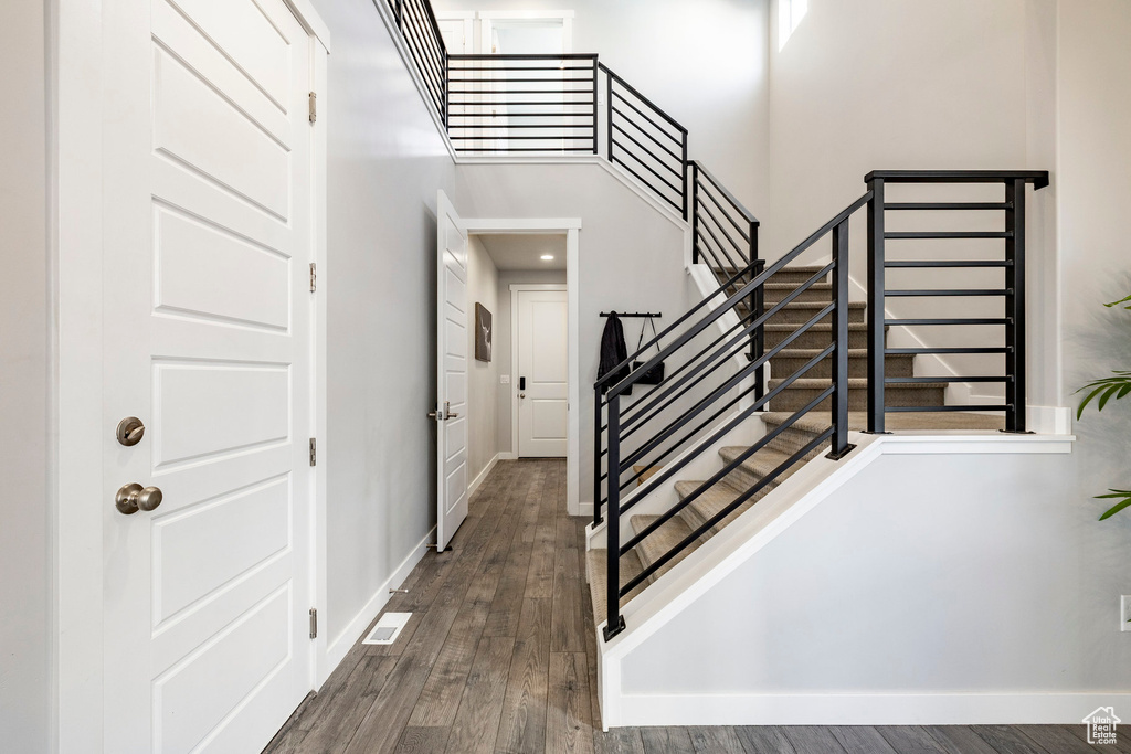 Staircase with wood finished floors, baseboards, and a high ceiling