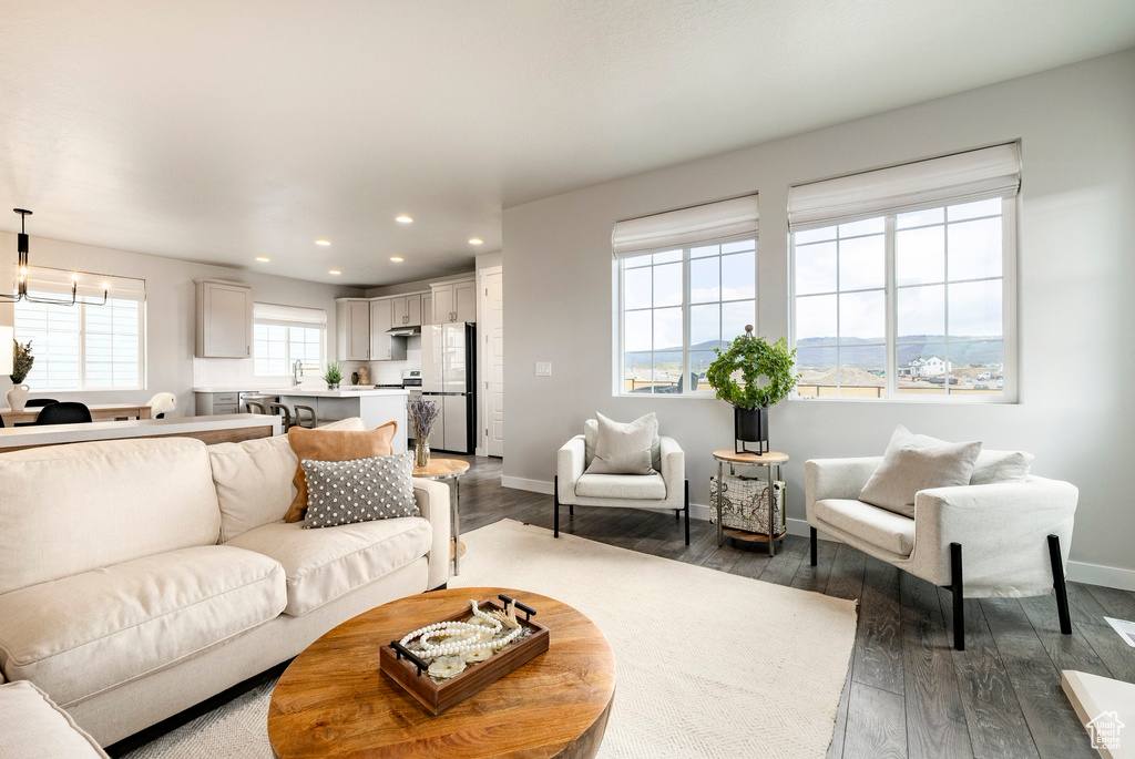 Living room with recessed lighting, dark wood-style floors, baseboards, and a chandelier