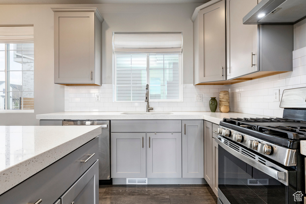 Kitchen featuring appliances with stainless steel finishes, gray cabinets, a sink, and under cabinet range hood