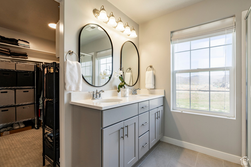 Full bathroom with healthy amount of natural light, baseboards, double vanity, and a spacious closet