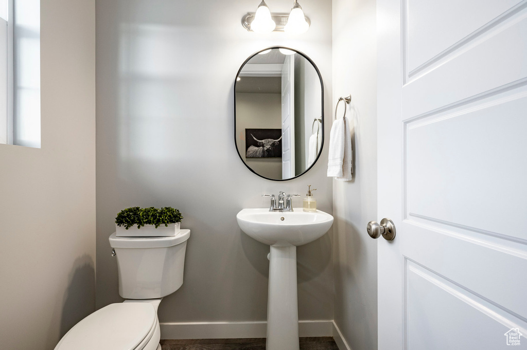 Half bathroom with toilet, baseboards, and a sink