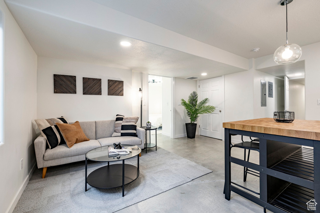 Living room with finished concrete floors, baseboards, recessed lighting, and electric panel