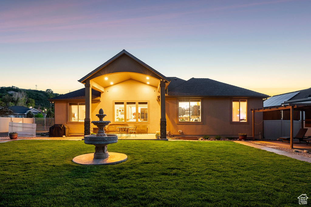 Back of property at dusk featuring stucco siding, a patio, and roof with shingles