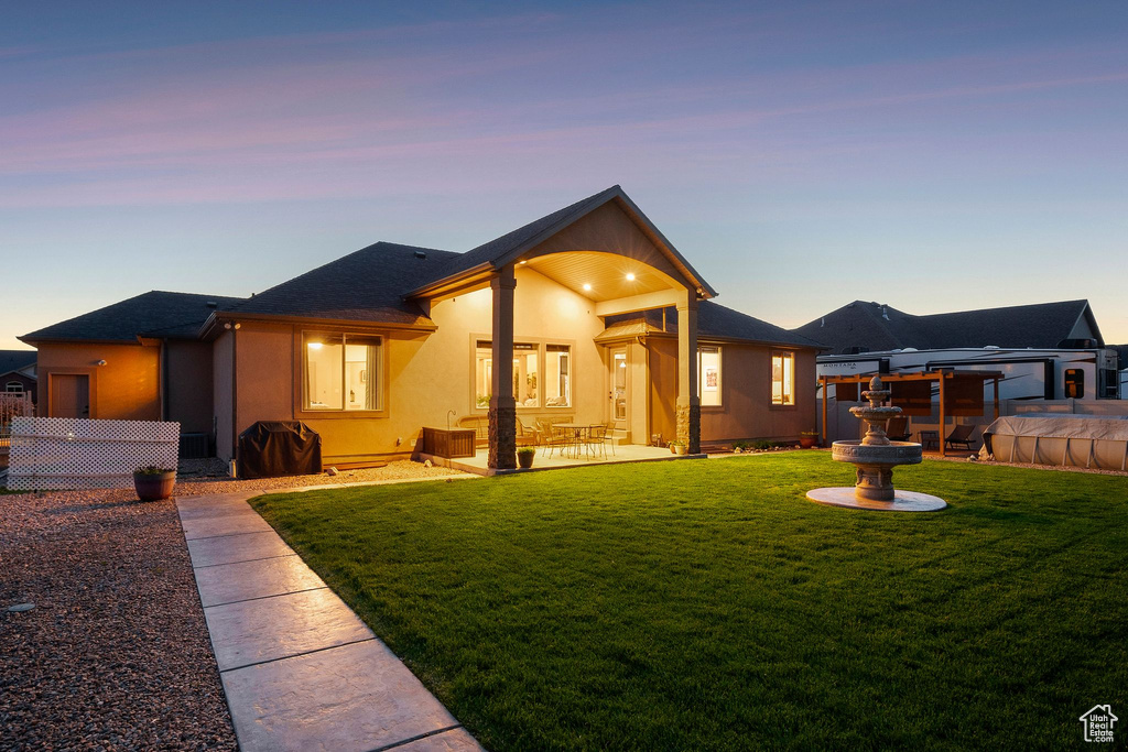 Rear view of house featuring stucco siding, a patio area, and a shingled roof
