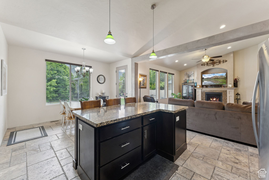Kitchen featuring stone tile floors, dark cabinetry, recessed lighting, a ceiling fan, and a lit fireplace
