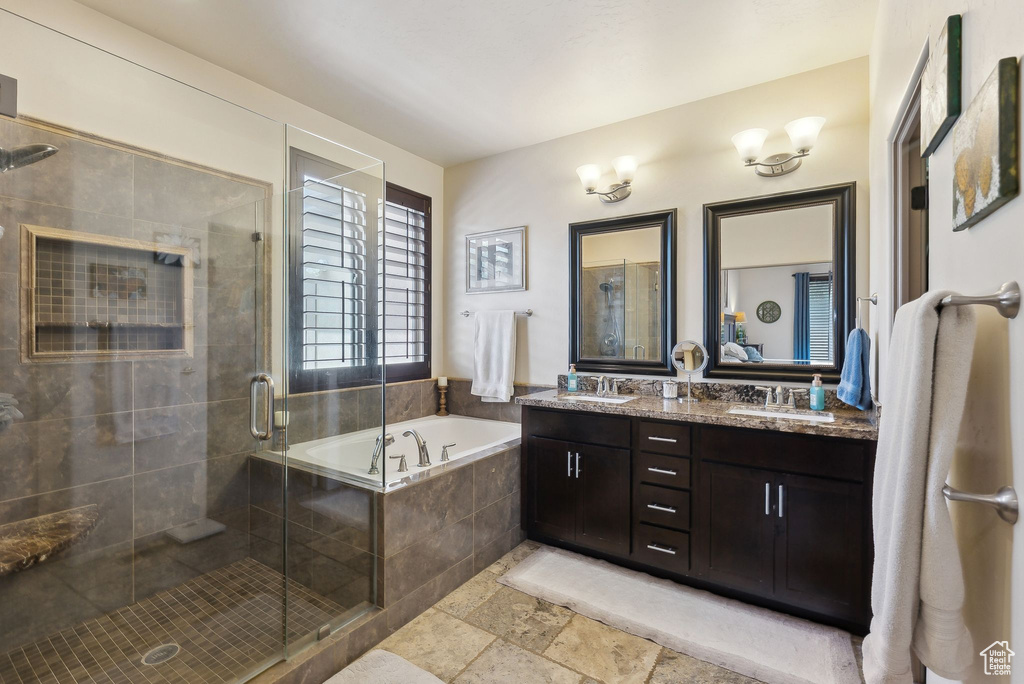 Full bathroom with a garden tub, a shower stall, double vanity, and stone tile flooring