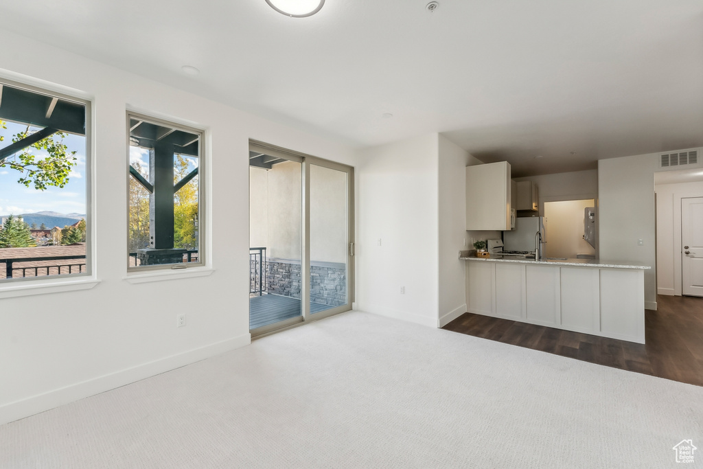 Unfurnished living room featuring dark carpet and baseboards