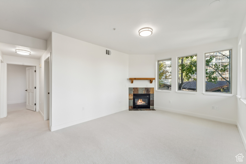 Unfurnished living room featuring carpet flooring, a fireplace, and baseboards