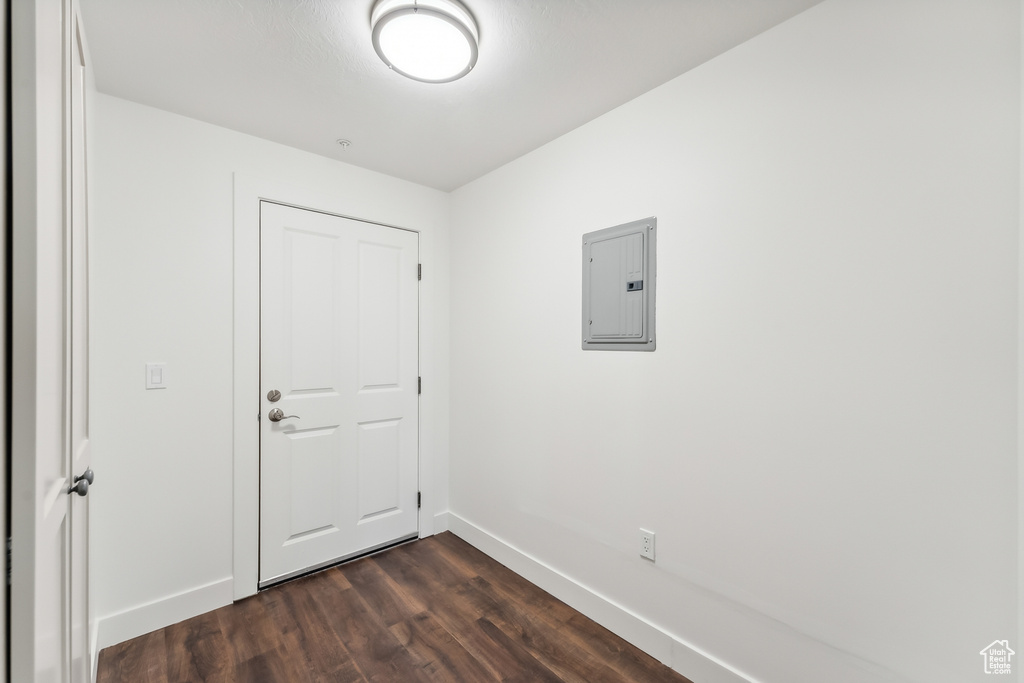 Empty room featuring electric panel, baseboards, and dark wood-type flooring