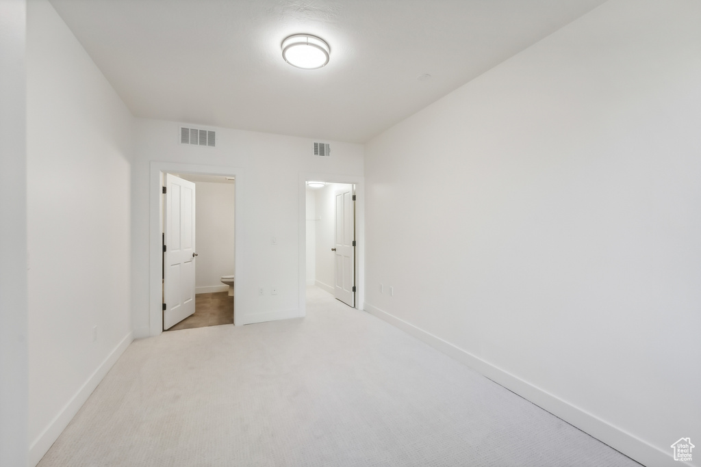 Unfurnished bedroom with baseboards, light carpet, and connected bathroom