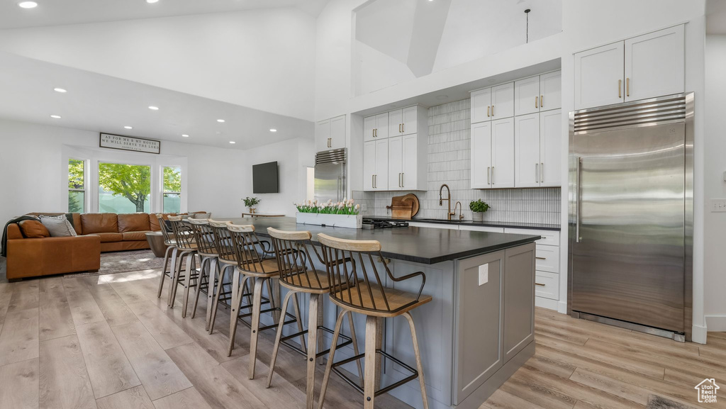 Kitchen with stainless steel built in refrigerator, a sink, dark countertops, light wood finished floors, and recessed lighting