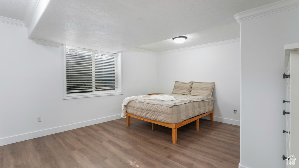Bedroom featuring crown molding, wood finished floors, and baseboards