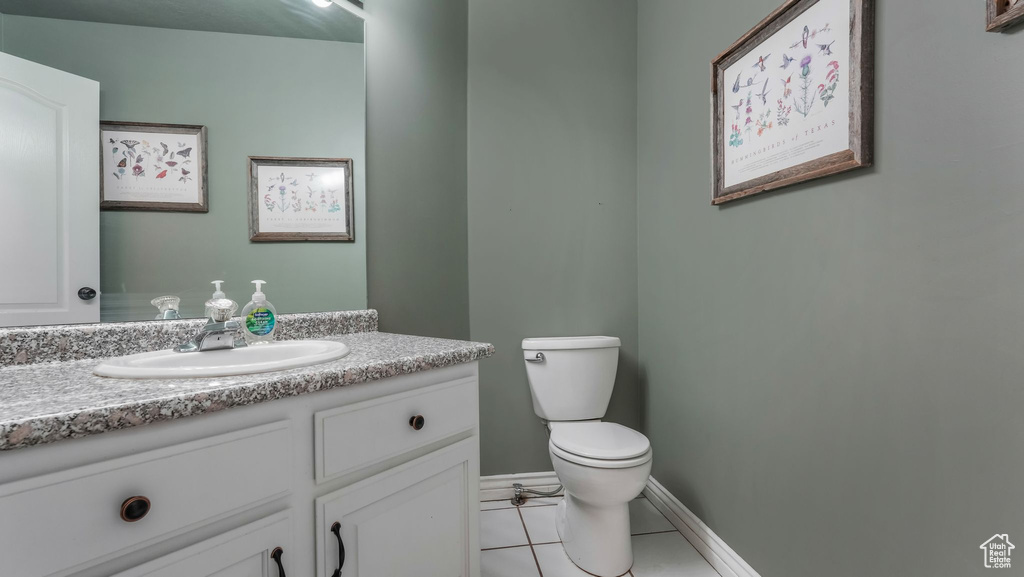 Half bath with tile patterned floors, toilet, vanity, and baseboards