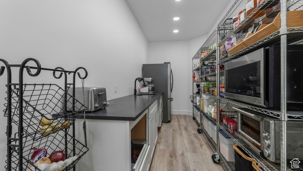 Kitchen featuring dark countertops, recessed lighting, light wood finished floors, freestanding refrigerator, and baseboards