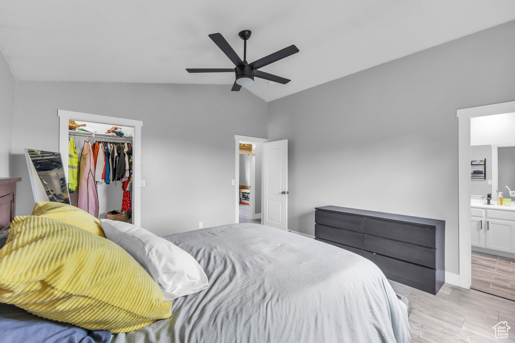 Bedroom with light wood-type flooring, a closet, ensuite bathroom, a walk in closet, and a ceiling fan