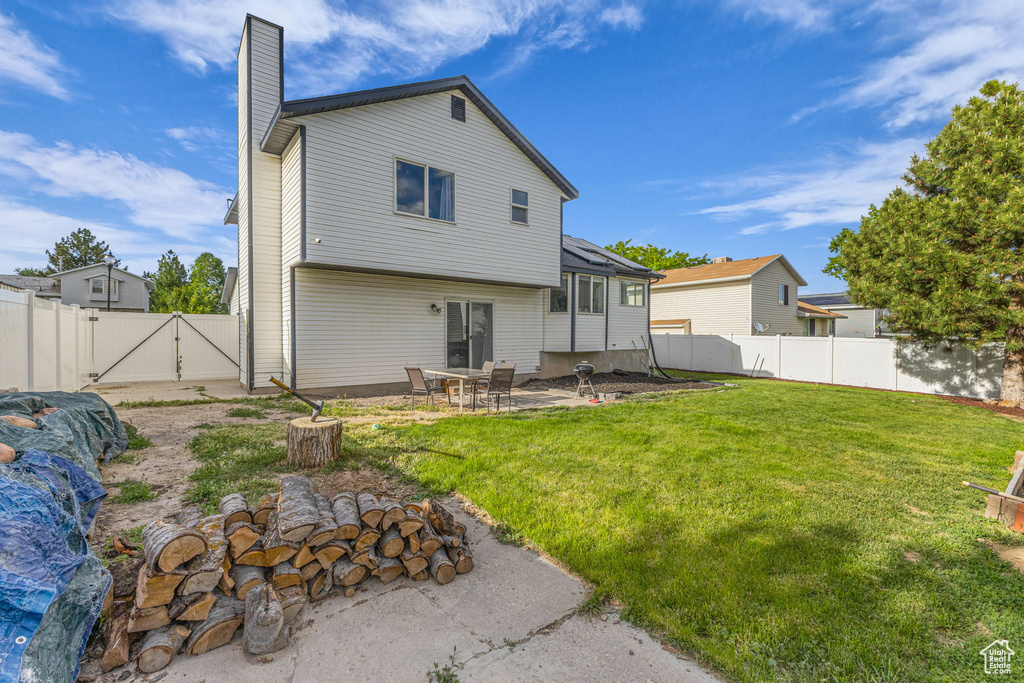Back of house featuring a gate, a chimney, and a patio