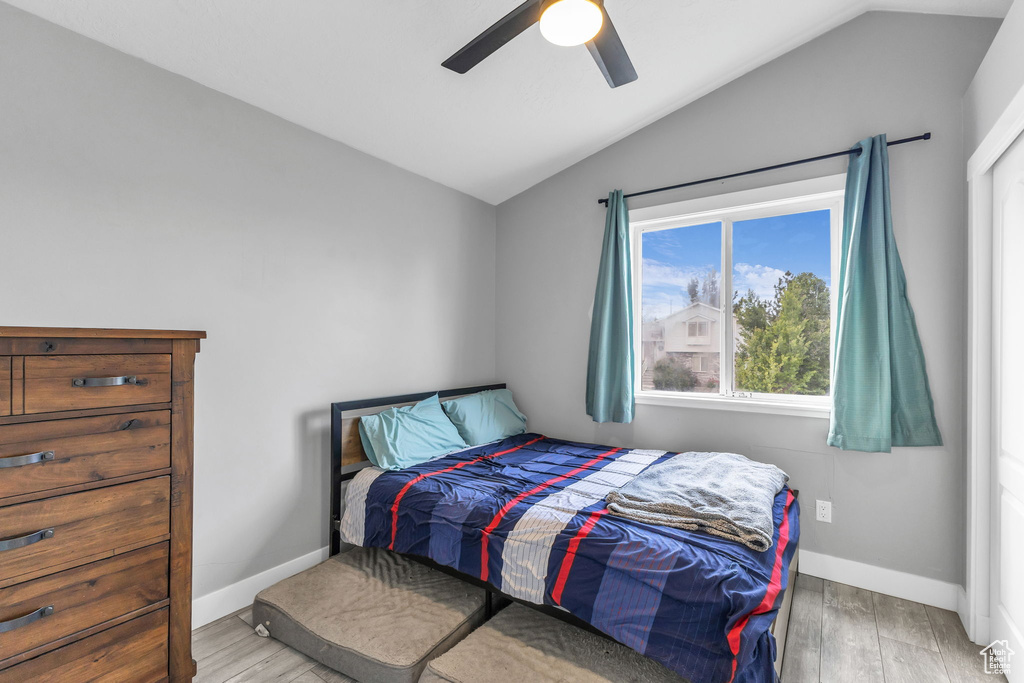 Bedroom with lofted ceiling, wood finished floors, baseboards, and ceiling fan
