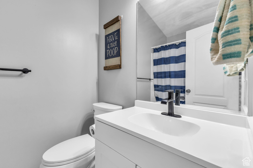 Full bathroom with toilet, vanity, and curtained shower