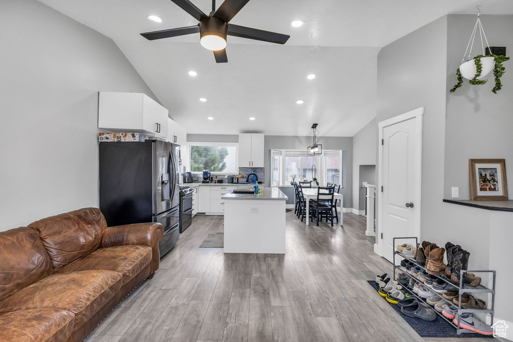 Living area featuring a ceiling fan, light wood-type flooring, recessed lighting, and high vaulted ceiling
