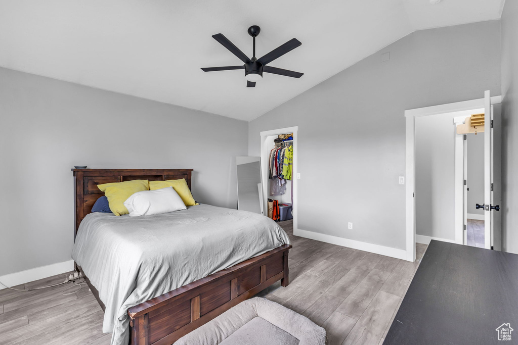 Bedroom featuring lofted ceiling, wood finished floors, a walk in closet, baseboards, and a closet