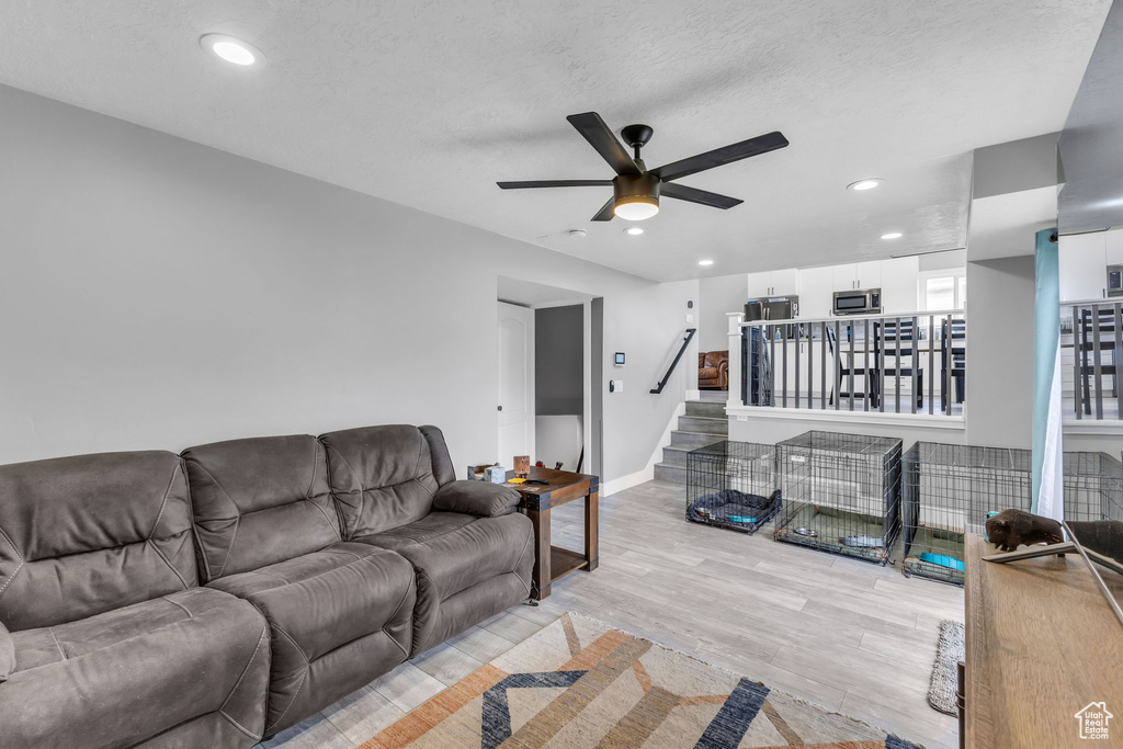 Living room with ceiling fan, light wood-style flooring, stairs, recessed lighting, and baseboards