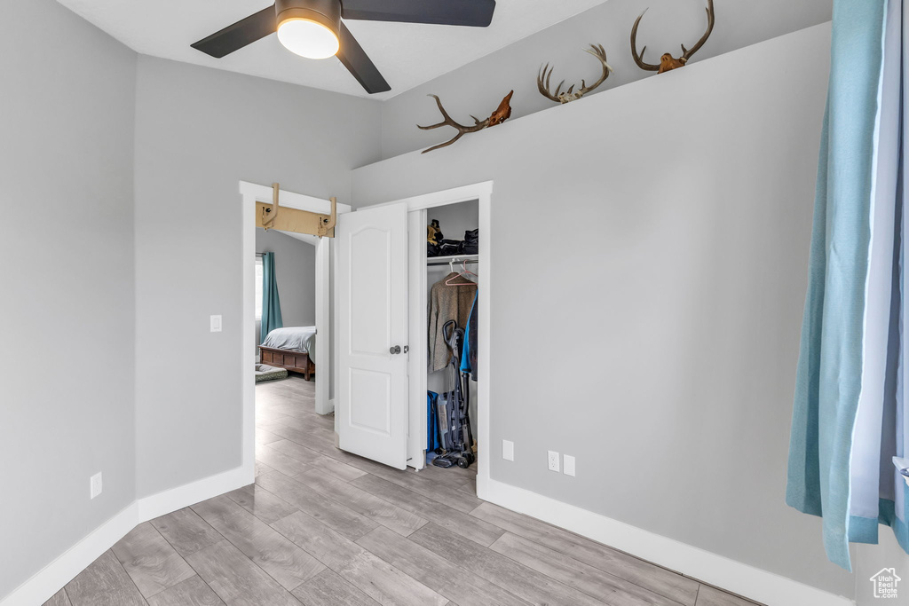 Unfurnished bedroom featuring wood finished floors, baseboards, a closet, vaulted ceiling, and ceiling fan