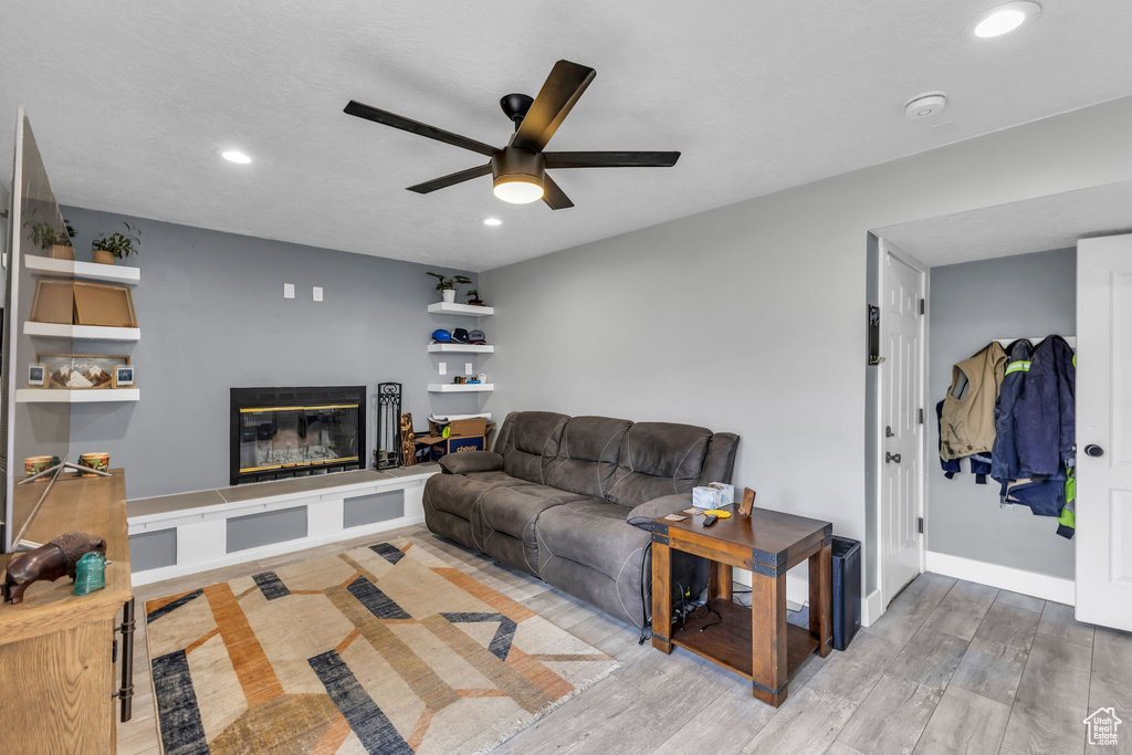 Living area with ceiling fan, recessed lighting, a glass covered fireplace, wood finished floors, and baseboards