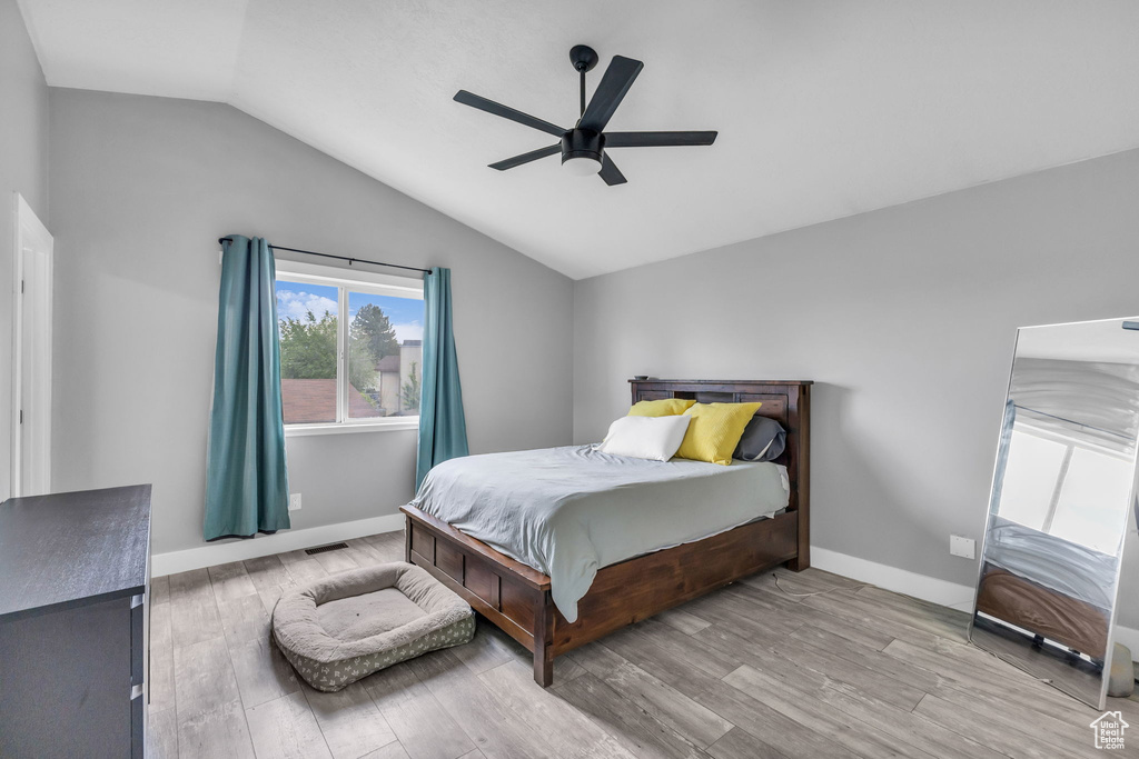 Bedroom with vaulted ceiling, wood finished floors, baseboards, and a ceiling fan