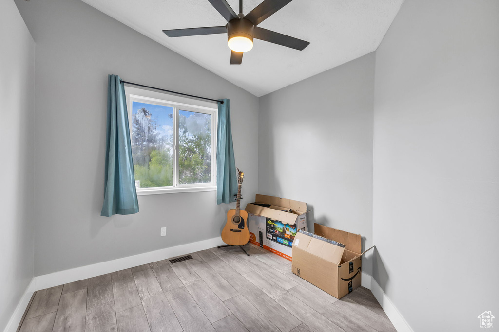 Empty room with vaulted ceiling, a ceiling fan, wood finished floors, and baseboards