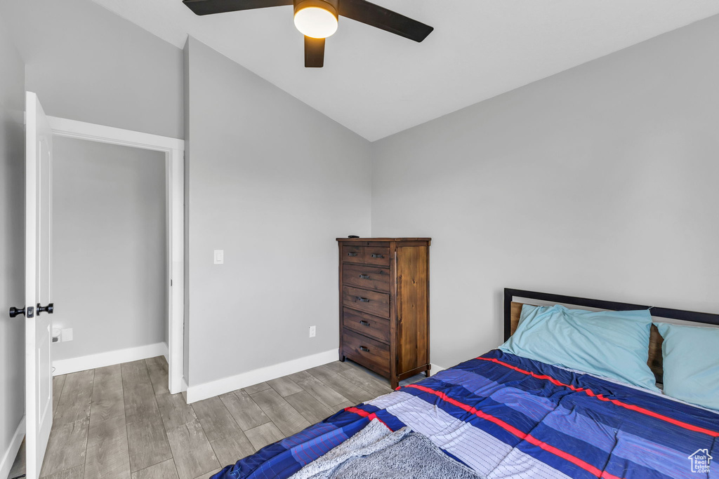 Bedroom with wood finished floors, lofted ceiling, baseboards, and a ceiling fan