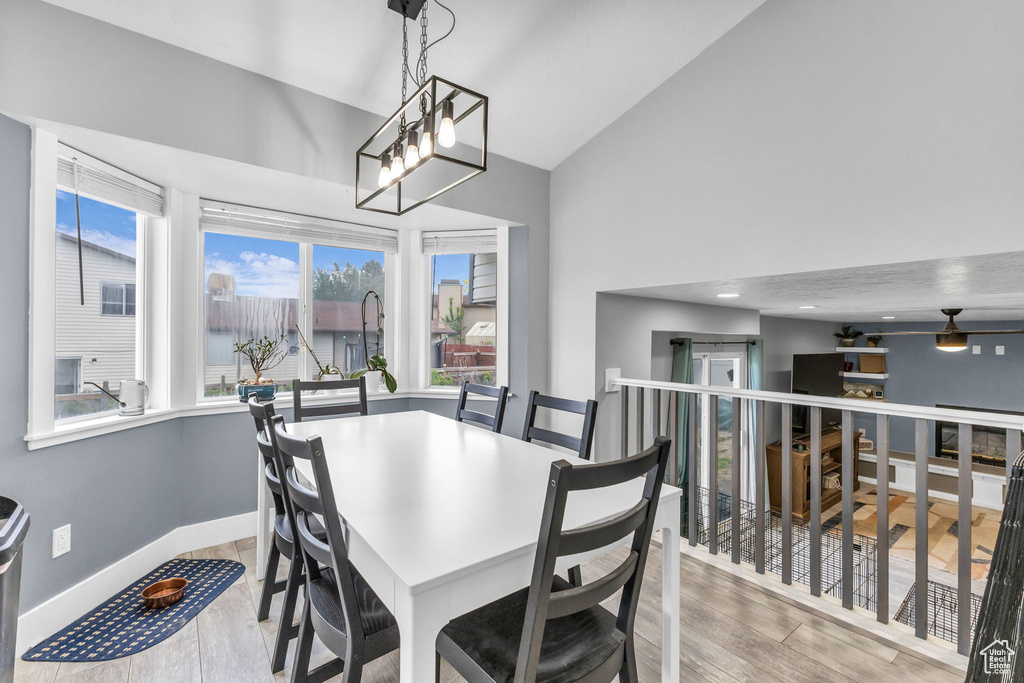 Dining room featuring high vaulted ceiling, wood finished floors, baseboards, and a chandelier