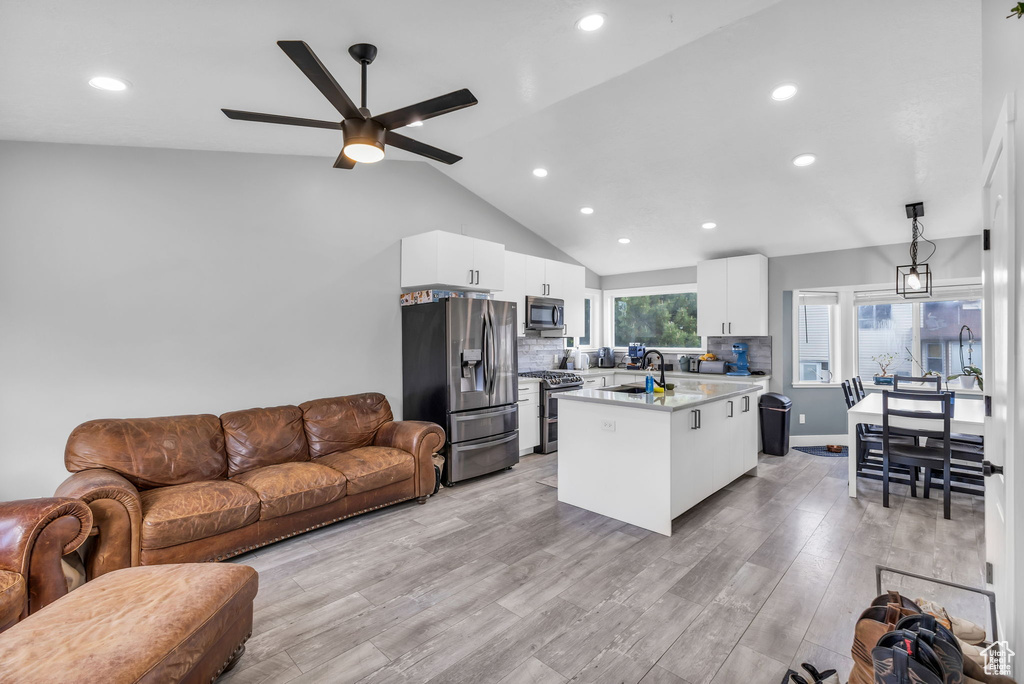 Living area with recessed lighting, ceiling fan, light wood finished floors, and high vaulted ceiling