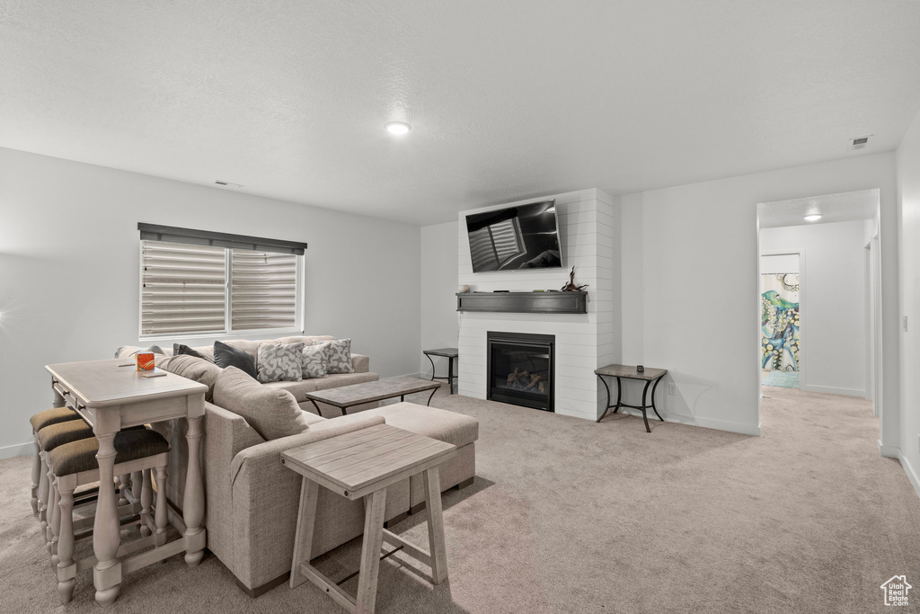 Living area featuring carpet flooring, a large fireplace, and baseboards