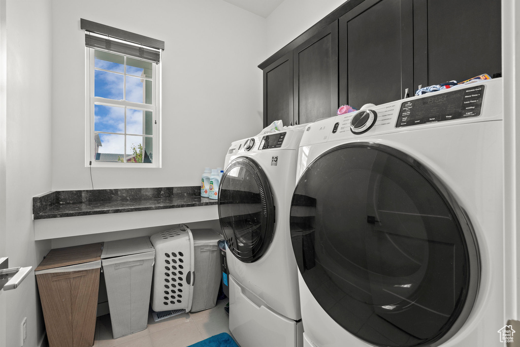 Laundry room featuring cabinet space, washing machine and clothes dryer, and light tile patterned flooring