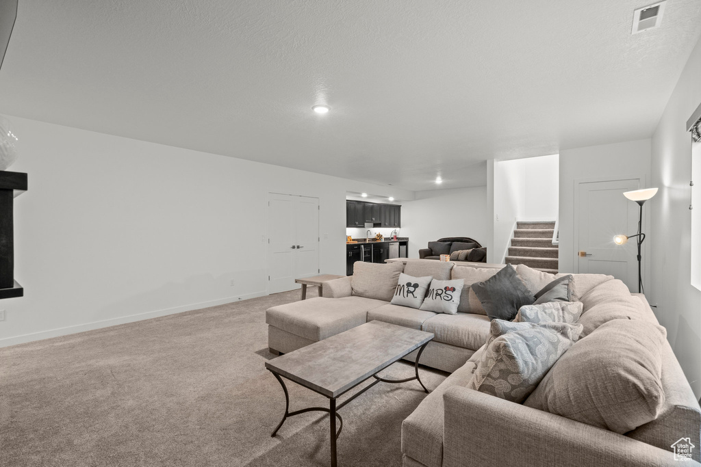 Living room featuring bar, light colored carpet, stairway, and baseboards