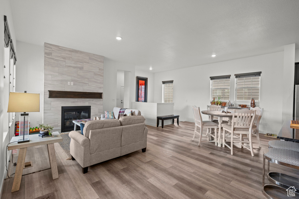 Living area with wood finished floors, recessed lighting, a tile fireplace, and baseboards