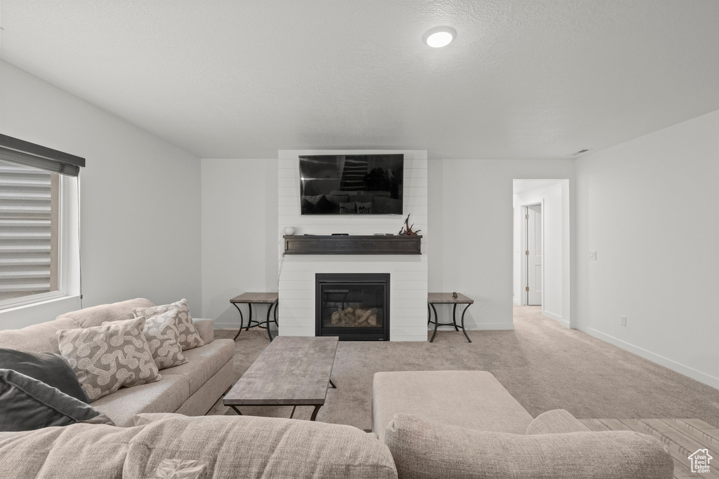 Carpeted living area with a large fireplace and baseboards