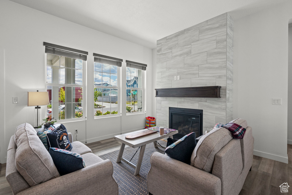 Living area with baseboards, a tiled fireplace, and wood finished floors