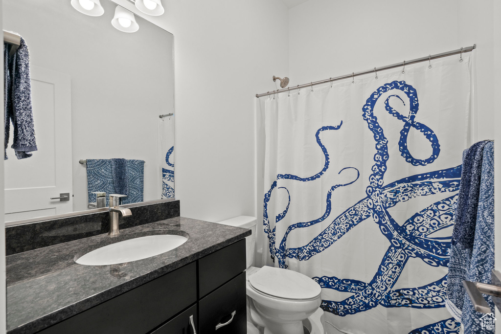 Bathroom with toilet, vanity, and curtained shower