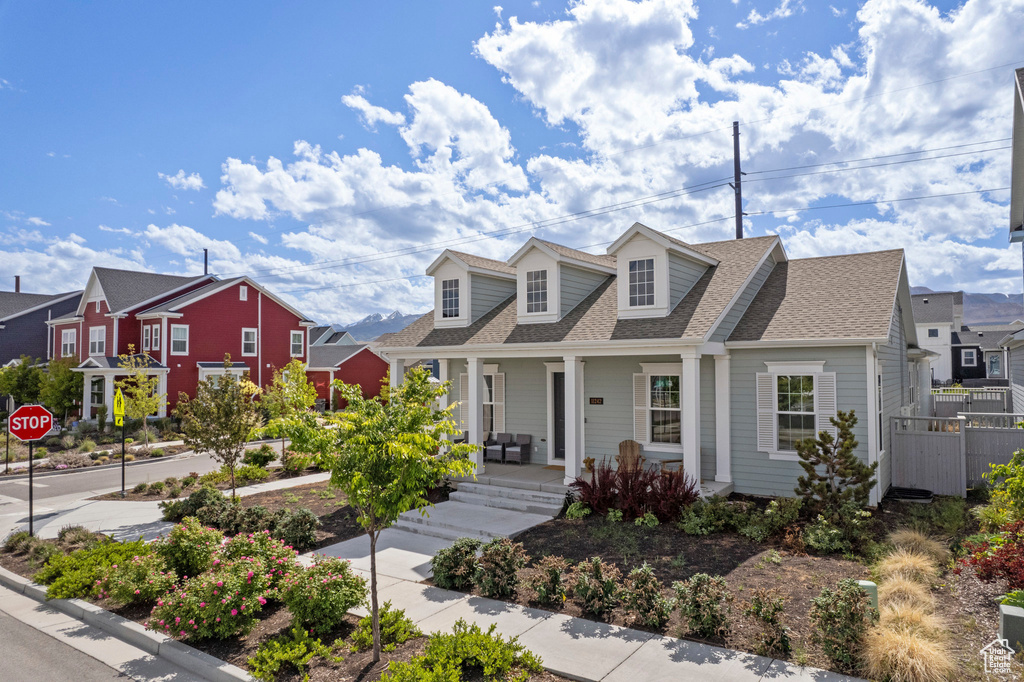 Cape cod house with covered porch, roof with shingles, and a residential view