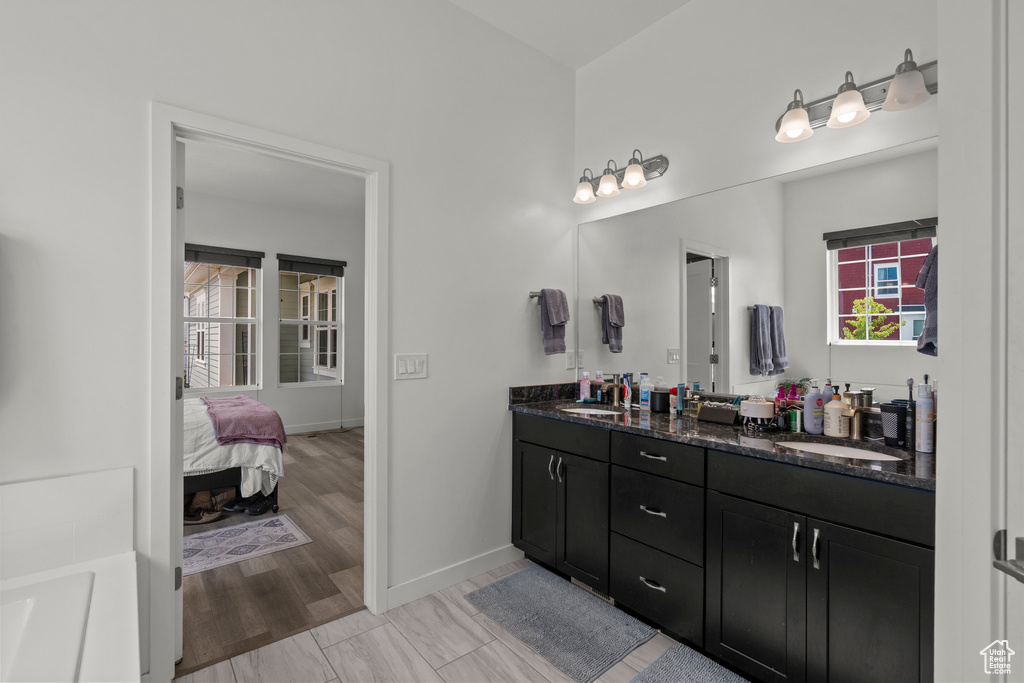 Ensuite bathroom featuring double vanity and baseboards