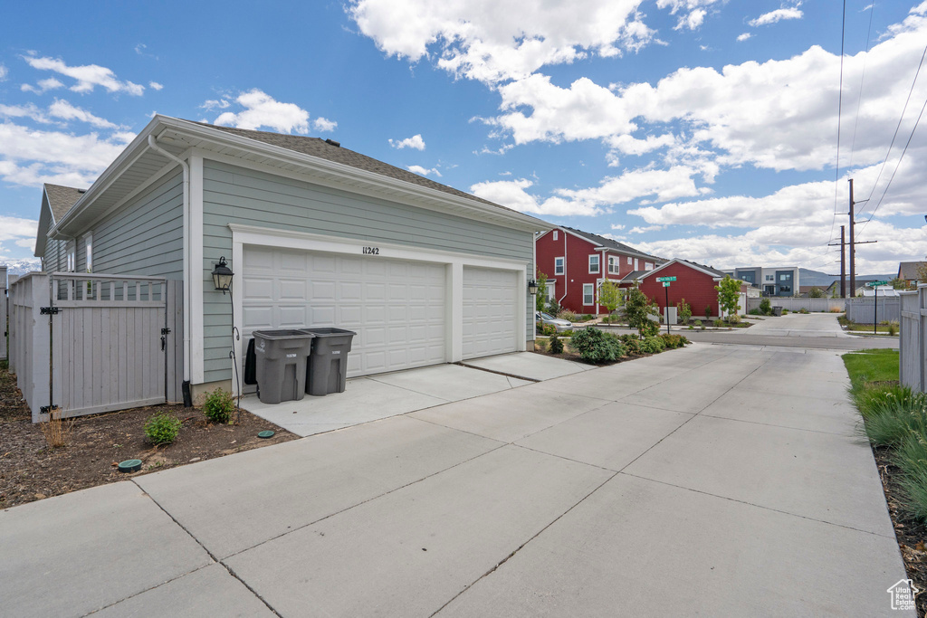 Garage with concrete driveway, a gate, and a residential view