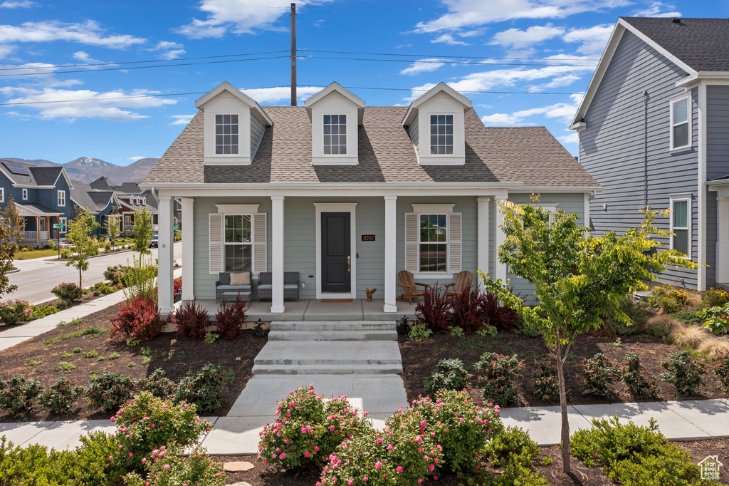 View of front of home featuring a shingled roof and covered porch