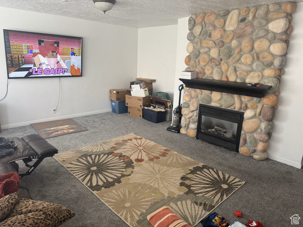 Living area featuring carpet floors, a textured ceiling, a fireplace, and baseboards