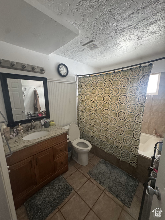 Bathroom featuring tile patterned flooring, a textured ceiling, vanity, toilet, and shower / tub combo