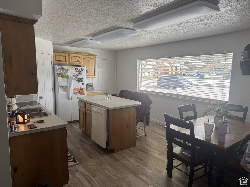 Kitchen with white appliances, a sink, dark wood-type flooring, a textured ceiling, and light countertops