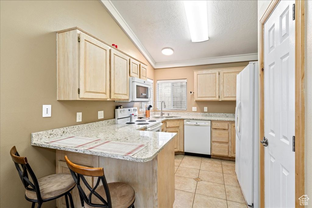 Kitchen with white appliances, light brown cabinetry, a peninsula, ornamental molding, and a textured ceiling