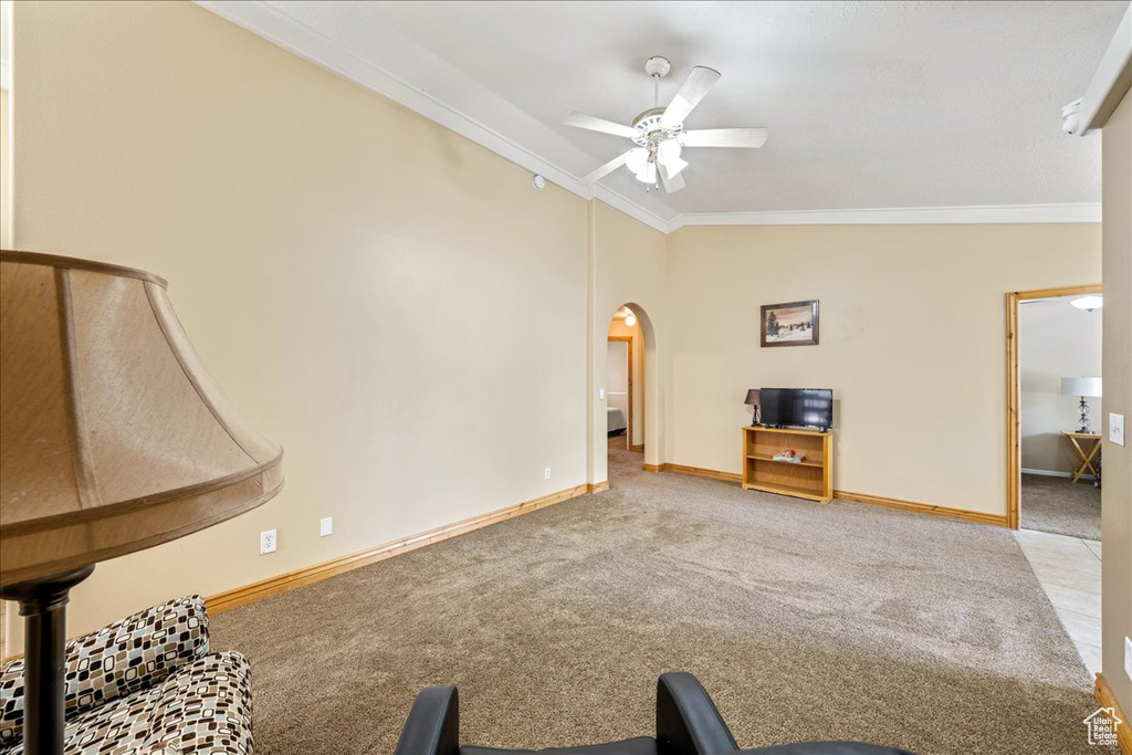 Unfurnished living room with carpet floors, ornamental molding, a ceiling fan, arched walkways, and vaulted ceiling