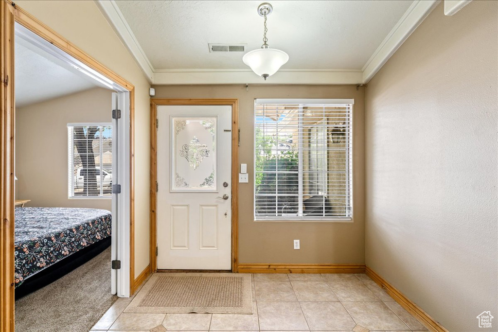 Foyer entrance with crown molding, light tile patterned floors, and baseboards