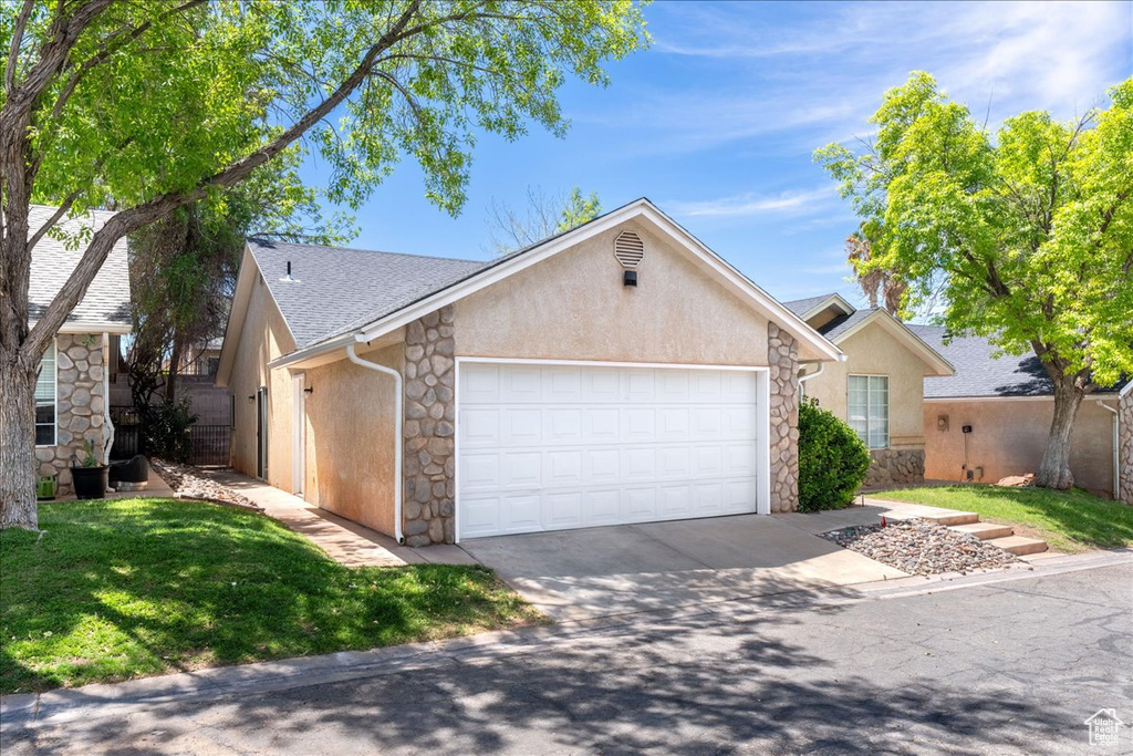 View of front of home featuring stone siding, an attached garage, and stucco siding